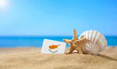 Wall Mural - Tropical beach with seashells and Cyprus flag. The concept of a paradise vacation on the beaches of Cyprus.