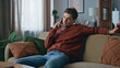 Bored guy calling cellphone relaxing at couch. Serious man talking smartphone