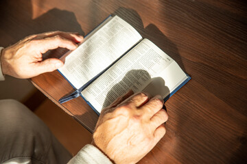Wall Mural - Hands of senior man holding Holy Bible at home. Lifestyle, natural aesthetic light.
