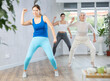 © JackF - Class of positive young mature women in sportswear performing expressive movements during joint workout in dance hall