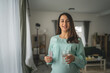 © Miljan Živković - Adult pregnant women stand and hold medicament glass of water at home