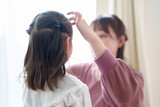 Fototapeta  - 女の子の髪をセットするお母さん
