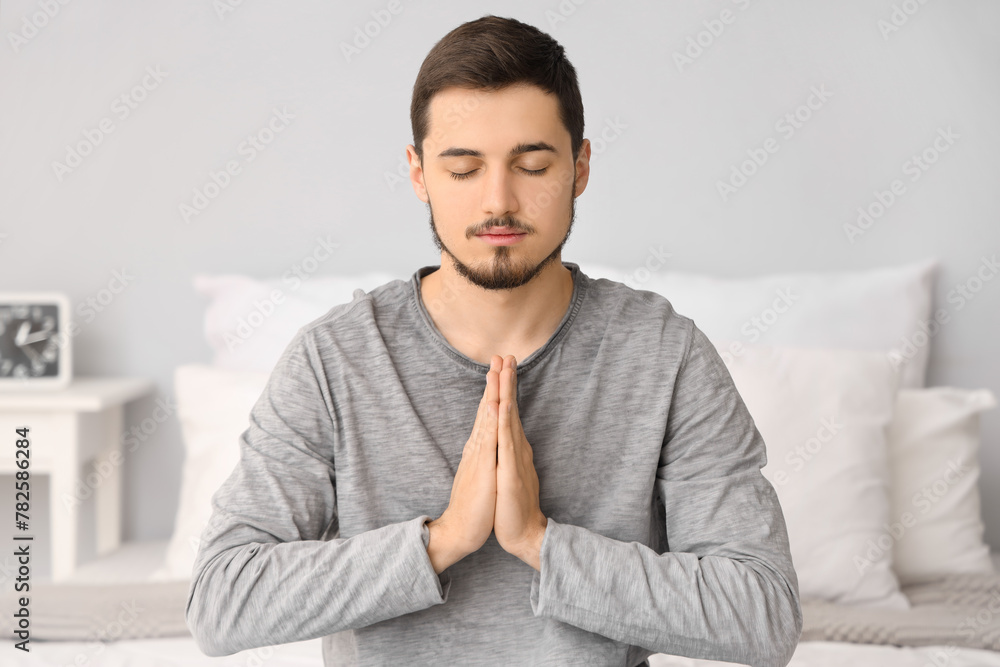 Young man praying in bedroom