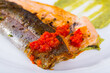 Portion of baked trout fillet with guacamole and tomato sauce