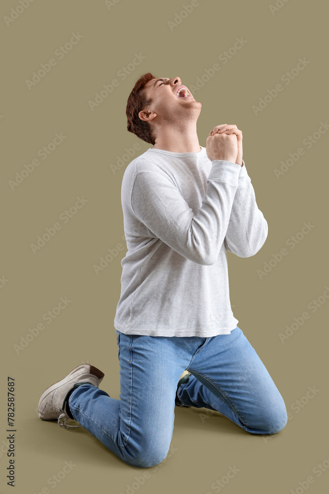 Young man praying on green background