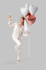 Poster - Happy bride in pajamas with champagne and balloons on light background. Hen Party