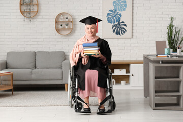 Wall Mural - Beautiful female Muslim graduate student in wheelchair with graduation cap and books at home