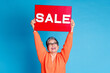 Photo portrait of lovely senior lady hold sale look raise plate banner dressed stylish orange garment isolated on blue color background