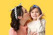 © Pixel-Shot - Beautiful pin-up woman kissing her daughter on yellow background
