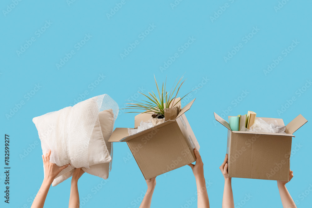 Women with moving boxes and pillows on blue background
