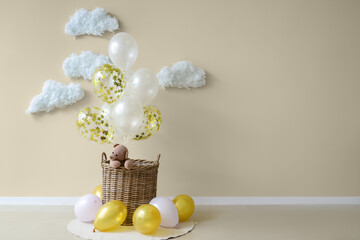 Wall Mural - Basket with toy bear, balloons and cotton clouds near light wall