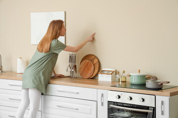 Wall Mural - Young woman pointing at mold on wall in kitchen