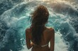 A woman in a bikini stands in the ocean, her hair blowing in the wind. Summer vacation concept, backdrop