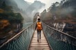 A backpacker crossing a suspension bridge high above a river