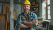 Bearded worker with a genuine smile poses confidently in a hard hat inside a woodworking workshop.