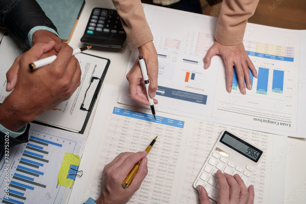 Confident group of business people pointing to graphs and charts to ...