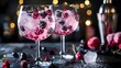 Close up of two nicely decorated cocktail glasses filled with a pink gin tonic beverage with frozen berries