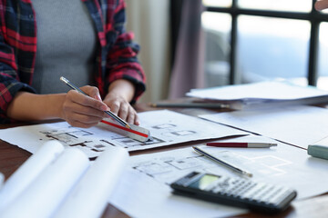 Wall Mural - Concept architect The engineer is measuring the distance to calculate and holding a pen pointing to the architect's structural schematic document on the table with blueprints in the office.