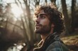 Portrait of a handsome young man with curly hair looking away in the forest