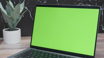Closeup of green screen laptop for website mockup on black marble background. Panning shot of computer with chroma key in 4K.