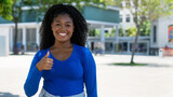 Fototapeta  - Pretty african american young adult woman showing thumb up with copy space in the city