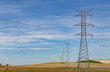 High voltage pylons for transporting electrical energy across crop fields on a spring day in southern Europe