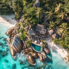 Sticker - A white sandy beach, palm trees and a blue ocean with large rocks with a house and pool.