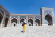 Happy attractive woman tourist in hat, posing at the entrance in Registan square Samarkand, Uzbekistan