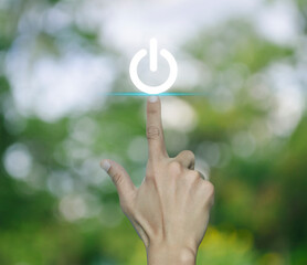 Canvas Print - Hand pressing power button icon over blur green tree in park, Start up business concept