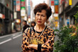 This Osaka auntie wearing a leopard print sweatshirt is an onlooker watching with arms folded and a grim face at the scene of the incident, accident, or fight. 
