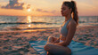 Young attractive woman meditates on the seashore against the backdrop of the sunset