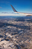 Fototapeta Natura - Airplane flying low over snowy mountains and preparing for landing to the airport, view from plane window of wing turbine and skyline