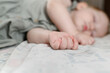 Focus on the toddler hands sleeps sweetly in a crib in bedroom during lunchtime nap, having played enough, he sees good dreams. Dream concept, happy child, childhood, parenthood, health concept.