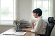 © Wasana - An adult woman sips her coffee while engaging with a laptop in a bright home office, reflecting a moment of tranquility amidst a busy workday.