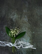 Lilies of the valley flowers with ribbons on abstract dark background. Romantic gentle symbol of spring season. top view