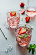 Ein Sommer Getränk mit Erdbeeren und Eiswürfel auf einem grauen Kachel Tisch. Nahaufnahme. 