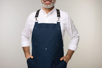 Poster - Man wearing kitchen apron on grey background, closeup. Mockup for design