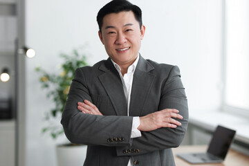 Wall Mural - Portrait of smiling businessman with crossed arms in office