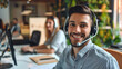 © Yuwarin - Smiling man call center operator with headset and female agent working in the background at office