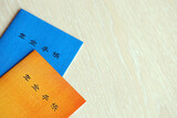 Fototapeta  - Japanese pension insurance booklets on table. Blue and orange pension book for japan pensioners close up