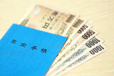 Fototapeta  - Japanese pension insurance book on table with yen money bills. Blue book for japan pensioners close up
