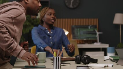 Wall Mural - medium shot of young african american team of programming engineers sitting down at office table to 