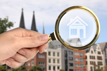 Wall Mural - Woman holding magnifying glass with illustration of house against city, closeup. Search for apartment