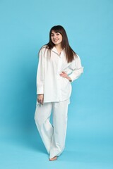 Wall Mural - Happy woman wearing pyjama on light blue background