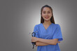 An Asian female doctor is holding a stethoscope on a gray background.