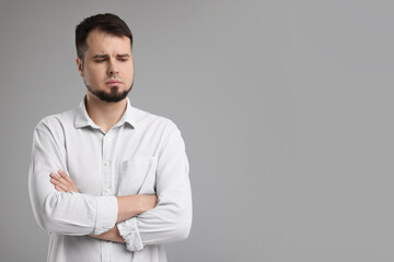 Wall Mural - Portrait of sad man with crossed arms on grey background, space for text