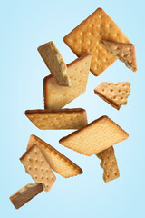Wall Mural - Tasty dry crackers falling on light blue background