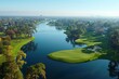 This high angle photo captures a sprawling green golf course with multiple water hazards and tree-lined fairways
