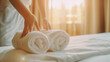 Close-up of Maid's Hands Arranging Fresh White Towels on Comfortable Hotel Bed. Clean Service. Housekeeping.