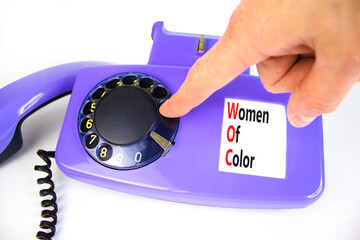 Wall Mural - WOC women of color symbol. Concept words WOC women of color on beautiful old disk phone. Beautiful white background. Businessman hand. Business WOC women of color social issues concept. Copy space.
